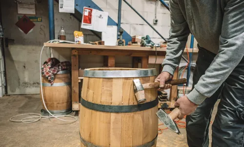 Cooper hammering hoops onto a barrel