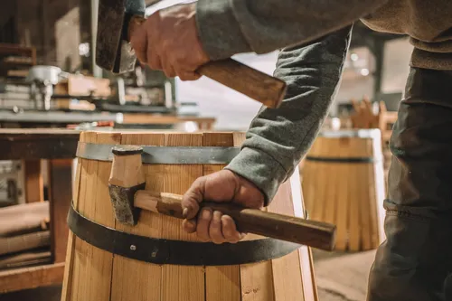 Cooper hammering a hoop onto an oak barrel
