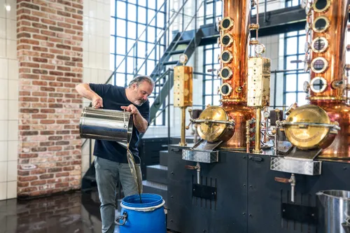 Monkey 47 distiller pouring maple syrup into the still
