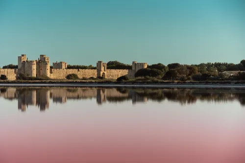 Fortified town walls reflected in a Camargue salt lagoon