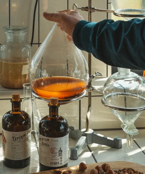 Hand adjusting a glass distillation apparatus filled with amber distillate