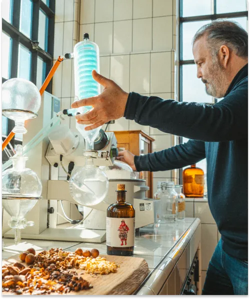 Distiller at a rotary evaporator with botanicals and a Monkey 47 Experimentum bottle