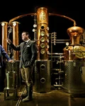 Two Monkey 47 distillers beside a gleaming copper still