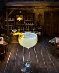 Bee's Knees cocktail with a lemon twist in a miniature saloon setting