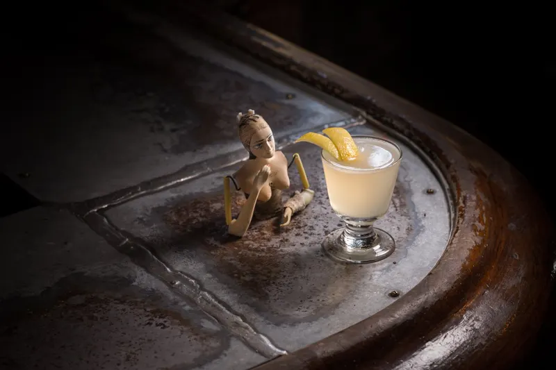 Corpse Reviver #2 with a lemon twist next to a figurine