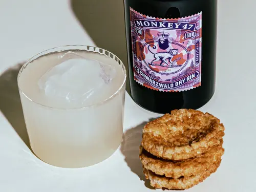 From Rags to Riches drink on ice with a Monkey 47 Sloe Gin bottle and biscuits