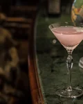 Aviation cocktail in a martini glass beside a globe
