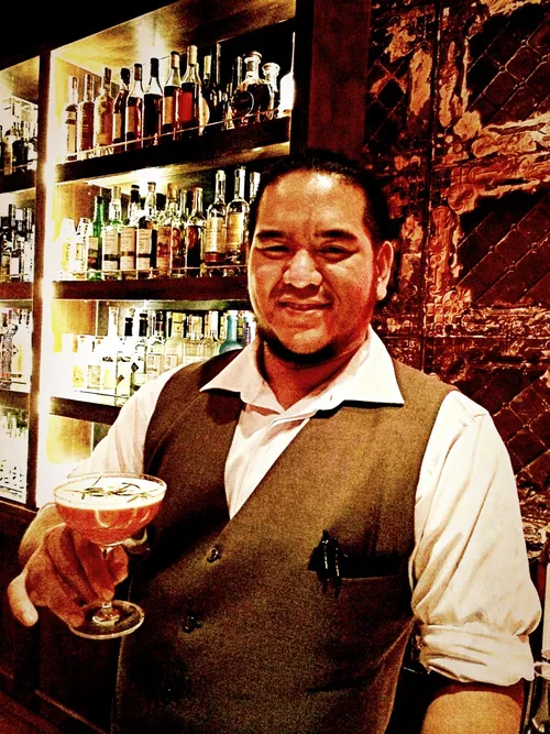 Smiling bartender presenting the L'Aiglon Screaming cocktail