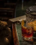 Negroni with an orange slice beside a glass jar