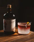 Perugia Sour next to a gin bottle