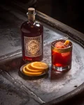 Sloe Gin Negroni with orange beside a Monkey 47 Sloe Gin bottle