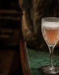The Clover Club in a stemmed glass beside old books