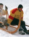 Two men racing a wooden horn sled through the snow
