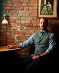 Jim Meehan seated at a desk in front of a brick wall
