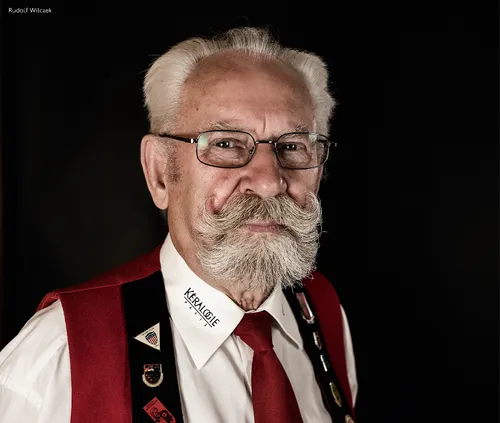 Grey-haired man with glasses and a moustache in traditional club costume