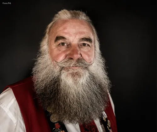 Man with a long grey beard in traditional costume with a red waistcoat