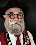 Bearded man with glasses and a black hat in traditional costume with badges