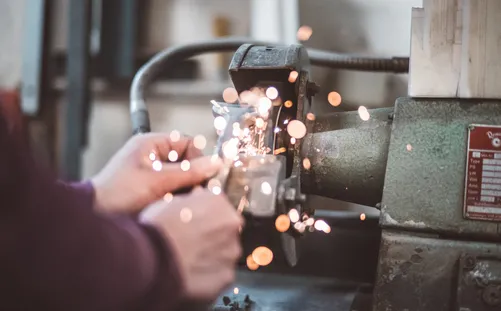 Hands grinding metal with sparks flying