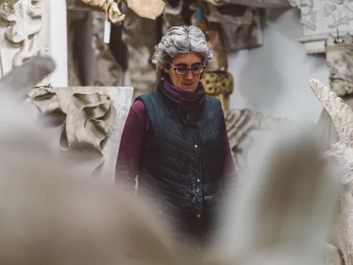 Stonemason standing among stone sculptures in her workshop