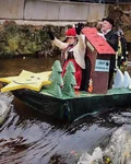 Decorated raft carrying costumed people over a weir in a river