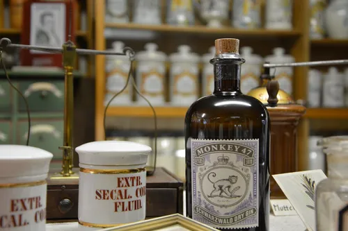 Monkey 47 bottle beside old apothecary jars in a pharmacy museum