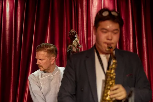 Saxophonist performing on stage in front of a red curtain