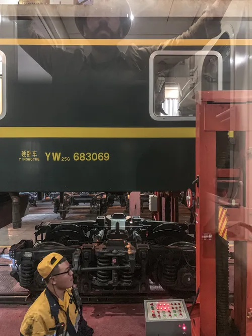 Green train carriage and a worker at the station