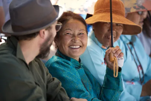 Smiling Mongolian women in traditional dress and hats with a traveller
