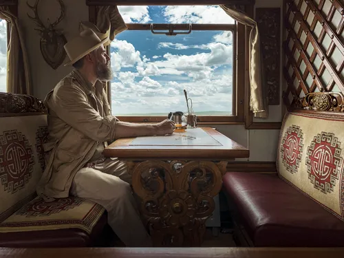 Traveller in a hat looking out of the dining car window