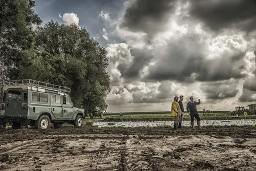 Land Rover and people in a field under a stormy sky