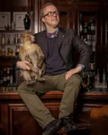 Man seated in a bar with a small monkey on his shoulder