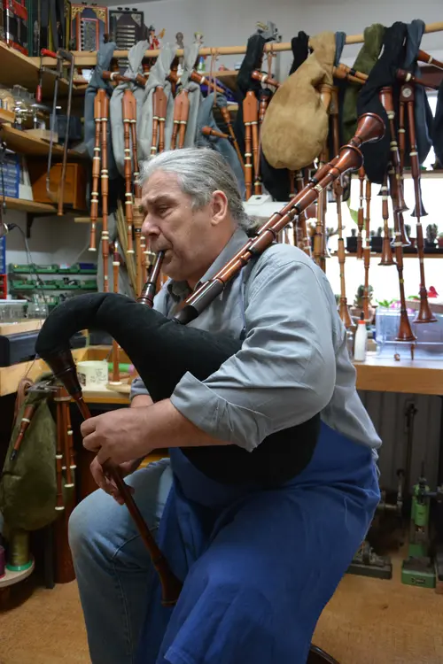 Black Forest piper playing bagpipes in his workshop