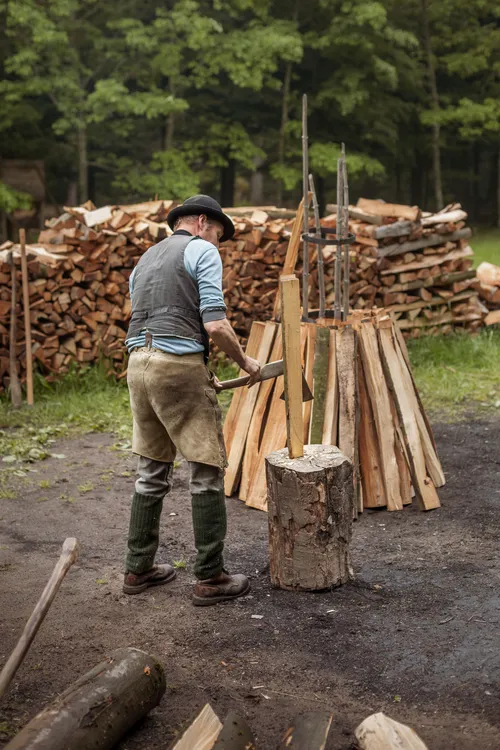 Charcoal burner stacking split logs for a kiln