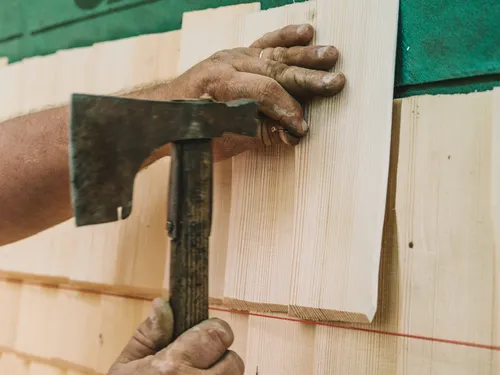 Hand hammering a wooden shingle into place