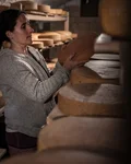 Cheesemaker turning cheese wheels in the cellar